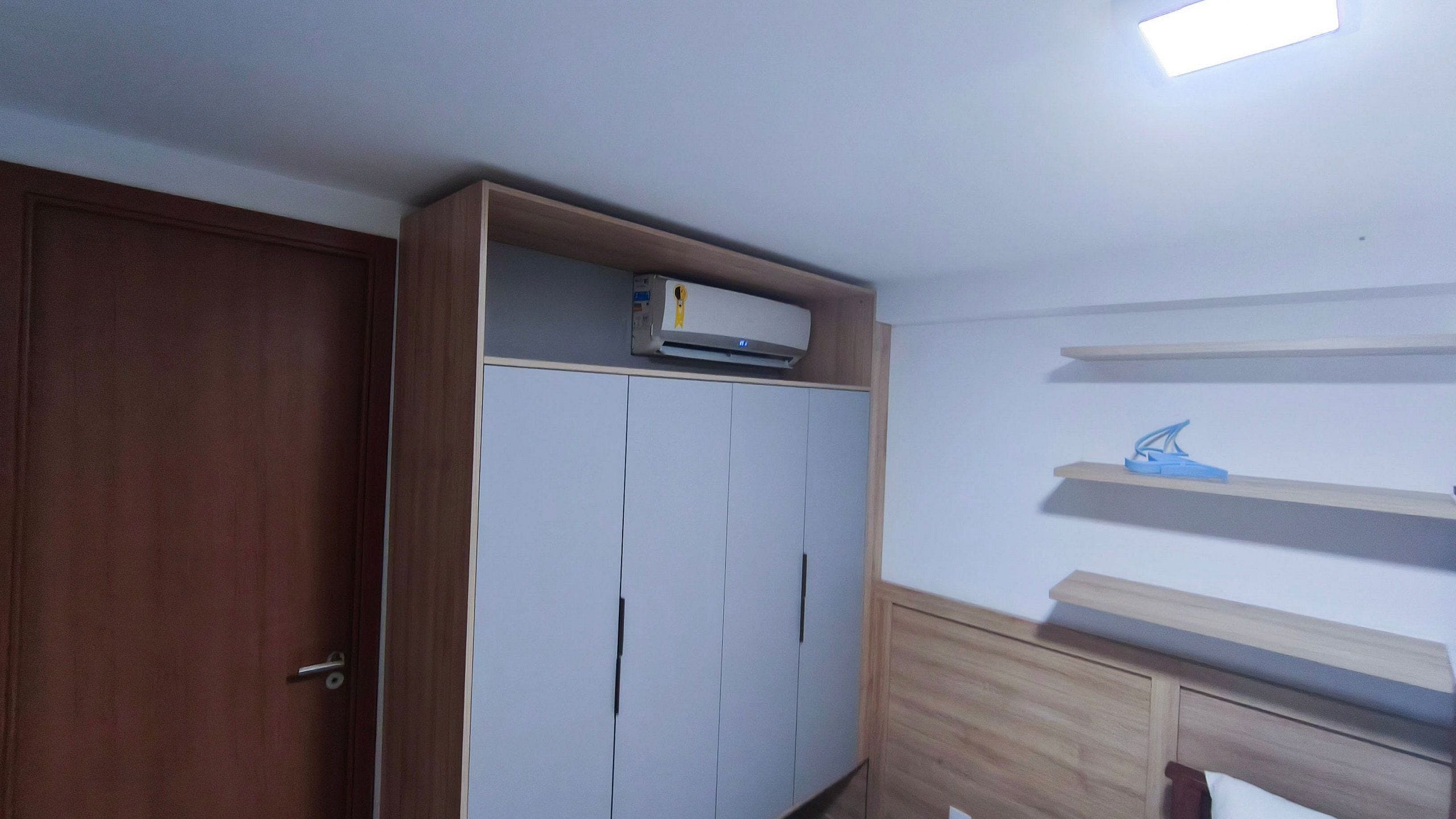 Quarto com guarda-roupa, ventoinha no teto e luminária.