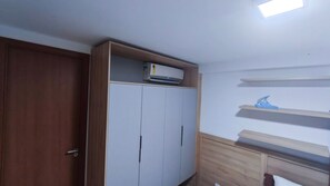 A room with a wardrobe, a ceiling fan, and a light fixture. - Max Carneiros Suítes  (Tamandaré)