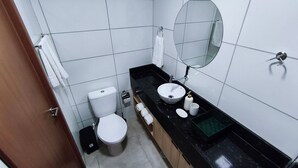 A small bathroom with a toilet, sink, mirror, and a towel rack. - Max Carneiros SuÃtes (Tamandaré)