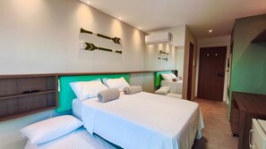 A hotel room with a bed, a bedside table, a mirror, and an air conditioning unit. - Max Carneiros Suítes  (Tamandaré)