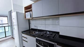 Uma cozinha moderna com armários brancos, bancada preta, fogão a gás e forno embutido.