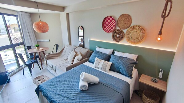 Una habitación de hotel con cama, sofá, mesa de comedor y sillas.