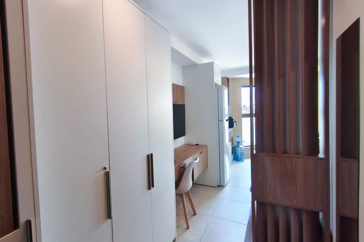 Un couloir avec une armoire blanche, une porte en bois et un coin cuisine comprenant un évier et un plan de travail.