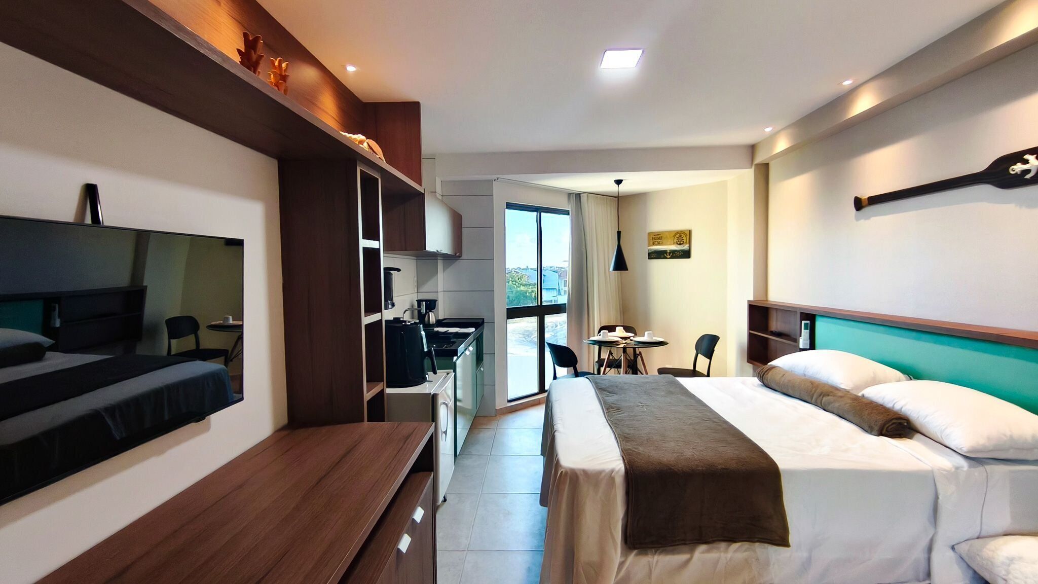 Ein modernes Hotelzimmer mit Bett, Schreibtisch, einer Küchenzeile und einem Essbereich.