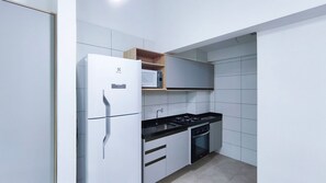 Eine kleine Küche mit Kühlschrank, Herd, Backofen und Mikrowelle auf einer Ablagefläche.