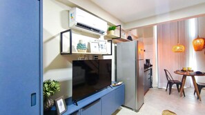 Une cuisine compacte équipée d’un téléviseur encastré, d’un réfrigérateur et d’un coin repas avec une table et des chaises.