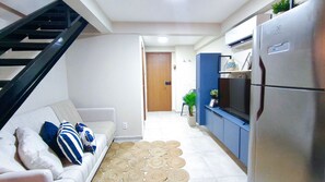 A modern kitchen with a built-in refrigerator, a dining area with a sofa and a small table, and a staircase leading to another level.