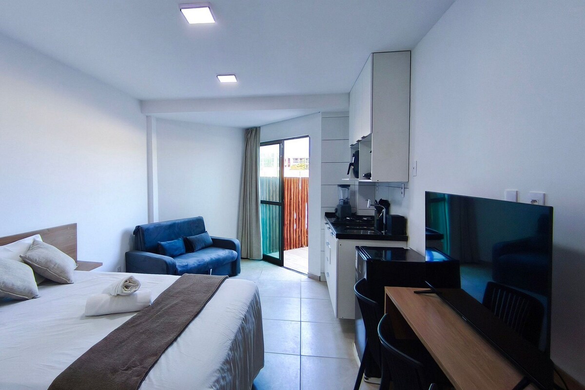 Ein Hotelzimmer mit Bett, Schreibtisch, Stuhl, Fernseher und einer Küchenzeile.