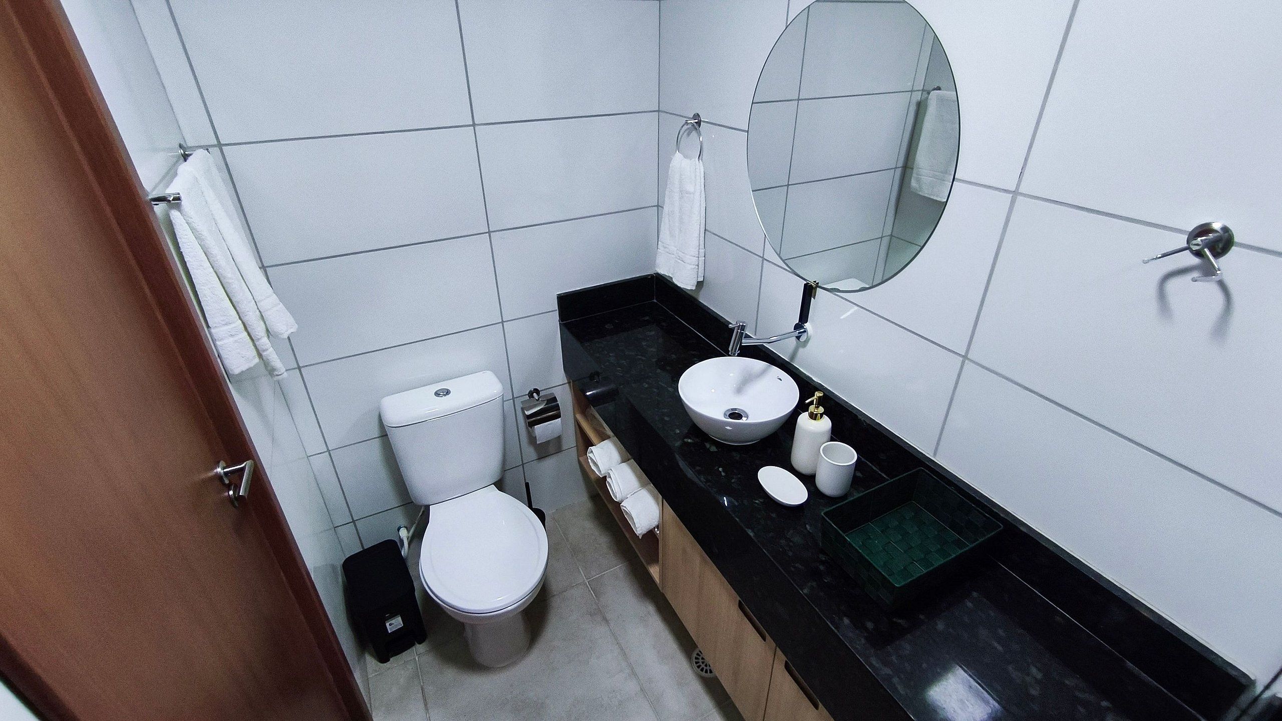 Een compacte badkamer met toilet, wastafel, spiegel en een handdoekhouder.