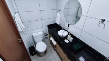 Een compacte badkamer met toilet, wastafel, spiegel en een handdoekhouder.