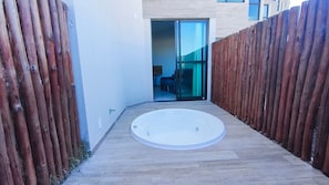 A narrow pathway leading to a circular hot tub with a wooden fence on either side.