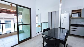 Eine moderne Küche mit Mikrowelle, Kühlschrank und Essbereich mit Glastisch und Stühlen.