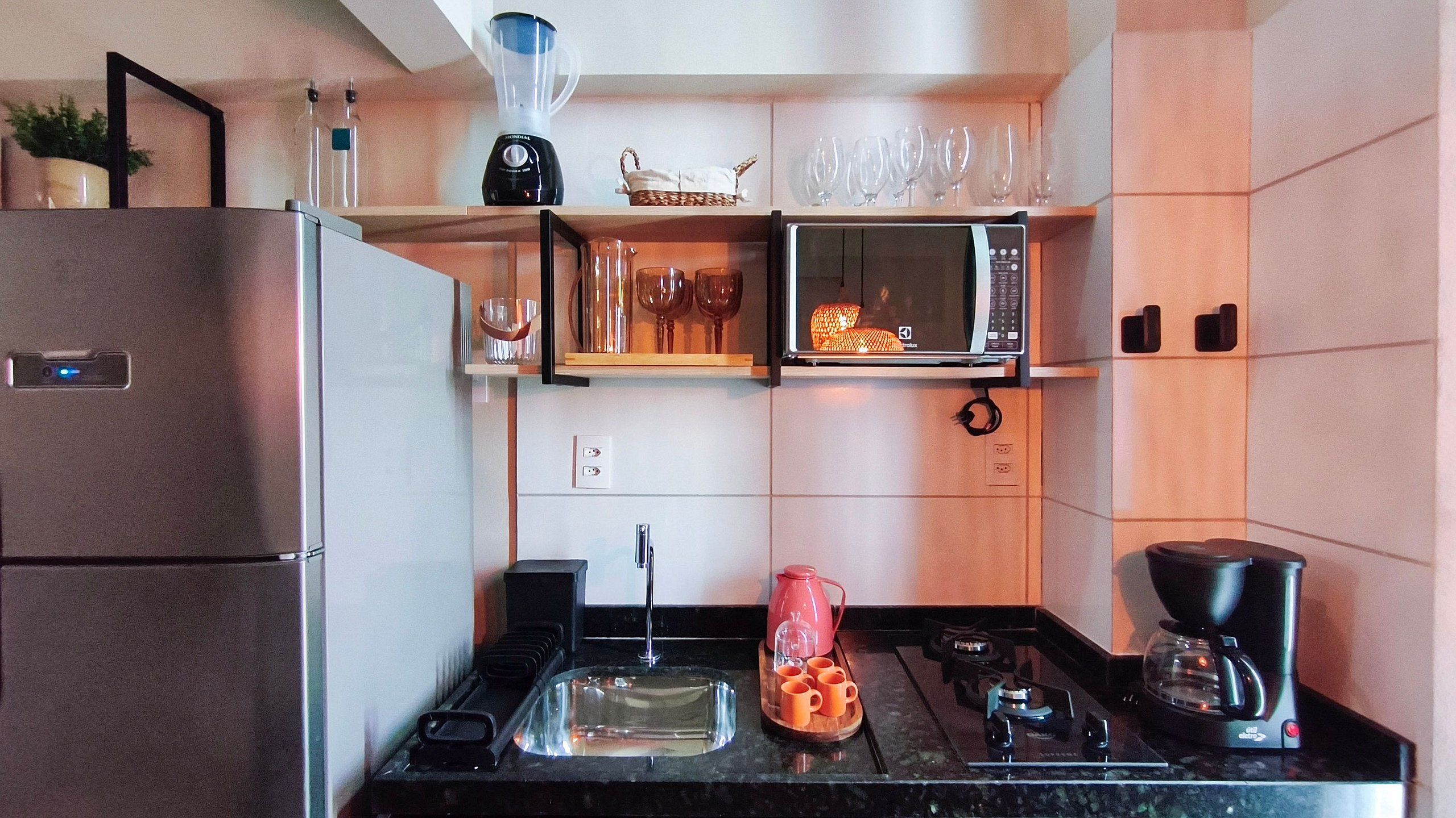 A compact kitchen with a refrigerator, microwave, stove, and a coffee maker.
