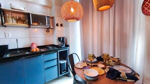 Una cocina compacta con microondas, cafetera y un comedor con mesa lista para dos.