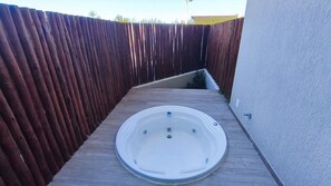 Un jacuzzi en una terraza de madera con un cerco de madera al fondo.
