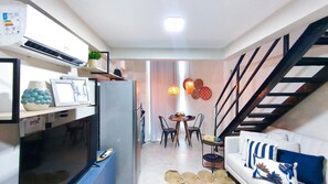 A compact living space with a dining area, a sofa, a staircase, and a kitchen area. - Max Carneiros Suítes  (Tamandaré)