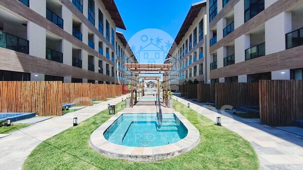 A modern building with a central pool, wooden fences, and a clear sky. - Max Carneiros SuÃtes (Tamandaré)