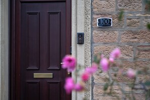 A dark wooden door with a brass mail slot and a house number sign on a stone wall. - Century House | 4BR | Free Parking | City Centre (Inverness)