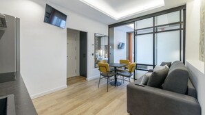 Ein modernes Wohnzimmer mit einer Couch, einem Esstisch mit Stühlen und einem an der Wand befestigten Fernseher.