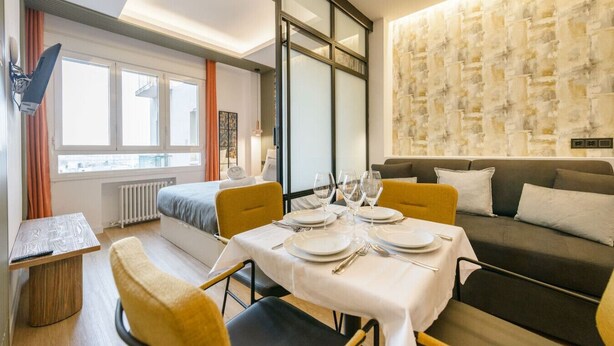 Ein modernes Hotelzimmer mit Essbereich, einer Couch und einem großen Fenster.