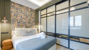 Ein modernes Hotelzimmer mit einem großen Bett, einer Wand mit Muster und einer Schiebeglasdoor zum Balkon.