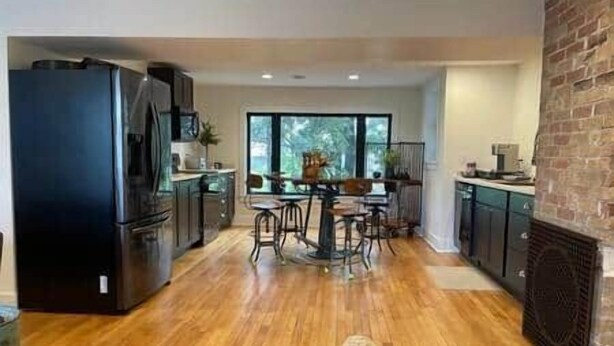 A modern kitchen with a dining area, wooden flooring, and a brick wall. - SchoolHouse Pent-House (Elkhart Lake)