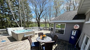 A wooden deck with a hot tub, outdoor seating, and a Skelly refrigerator. - SchoolHouse Pent-House (Elkhart Lake)