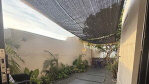 A narrow outdoor corridor with a checkered floor, potted plants, and a shaded area with a patterned ceiling. - Cozy Hideaway near Mambo Beach - Private Garden (Willemstad)