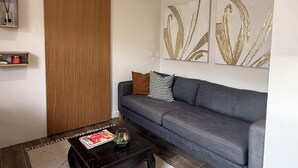 A living room with a sofa, a coffee table, a sliding door, and abstract wall art. - Cozy Hideaway near Mambo Beach - Private Garden (Willemstad)
