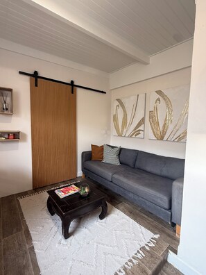 Ein Wohnzimmer mit Sofa, Couchtisch, einer Schiebetür und abstrakter Wandkunst.