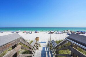 A beach with wooden walkways leading to the shore, clear blue sky, and umbrellas on the sand. - Driftwood Townhomes #3- Liv Salty (Miramar Beach)