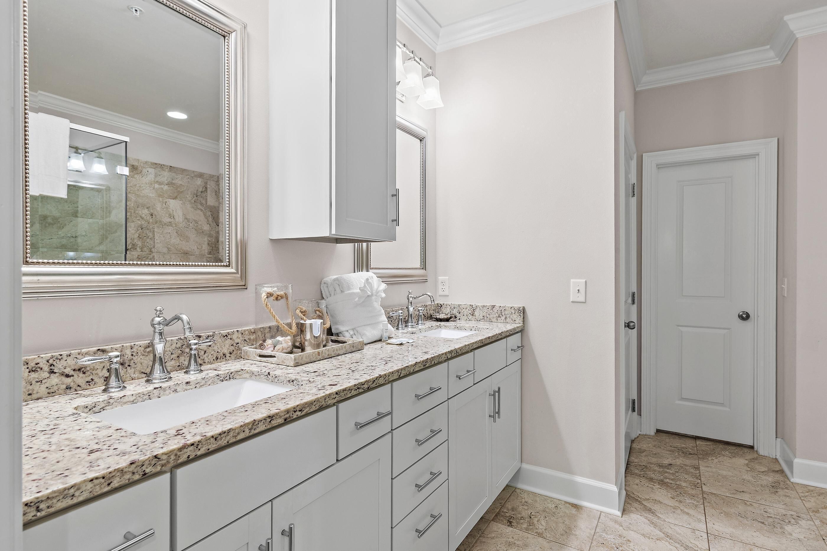 A bathroom with a double sink, a large mirror, and a vanity with drawers.