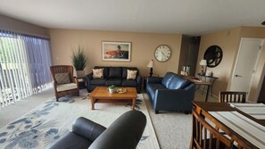 A living room with a sofa, armchairs, a coffee table, and a dining table. - Charming 2BR Condo in Lake Geneva - Walk to Pool, Tennis & Downtown! (Lake Geneva)