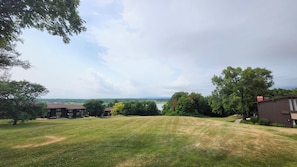 A residential area with a grassy lawn, trees, and buildings in the background. - Charming 2BR Condo in Lake Geneva - Walk to Pool, Tennis & Downtown! (Lake Geneva)