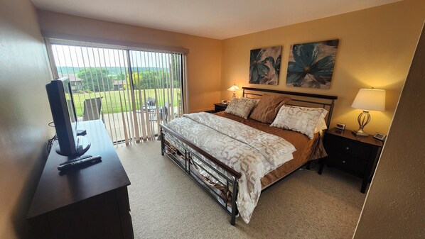 A bedroom with a bed, a TV, a desk, and a balcony with a view. - Charming 2BR Condo in Lake Geneva - Walk to Pool, Tennis & Downtown! (Lake Geneva)