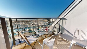Ein Balkon mit Tisch für Zwei, mit Blick auf einen Hafen voller Boote.