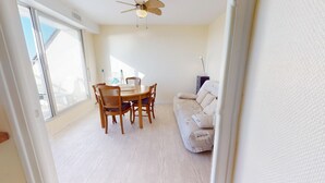 Une pièce comprenant une table à manger, des chaises, un canapé et un ventilateur de plafond.