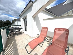 Un balcone con tavolo, sedie e due sdraio.