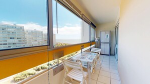 A balcony with a table and chairs, a refrigerator, and a view of buildings and the sea. - Pavois d'Azur - Sea view apartment 100m from the beach (Saint-Hilaire-de-Riez)