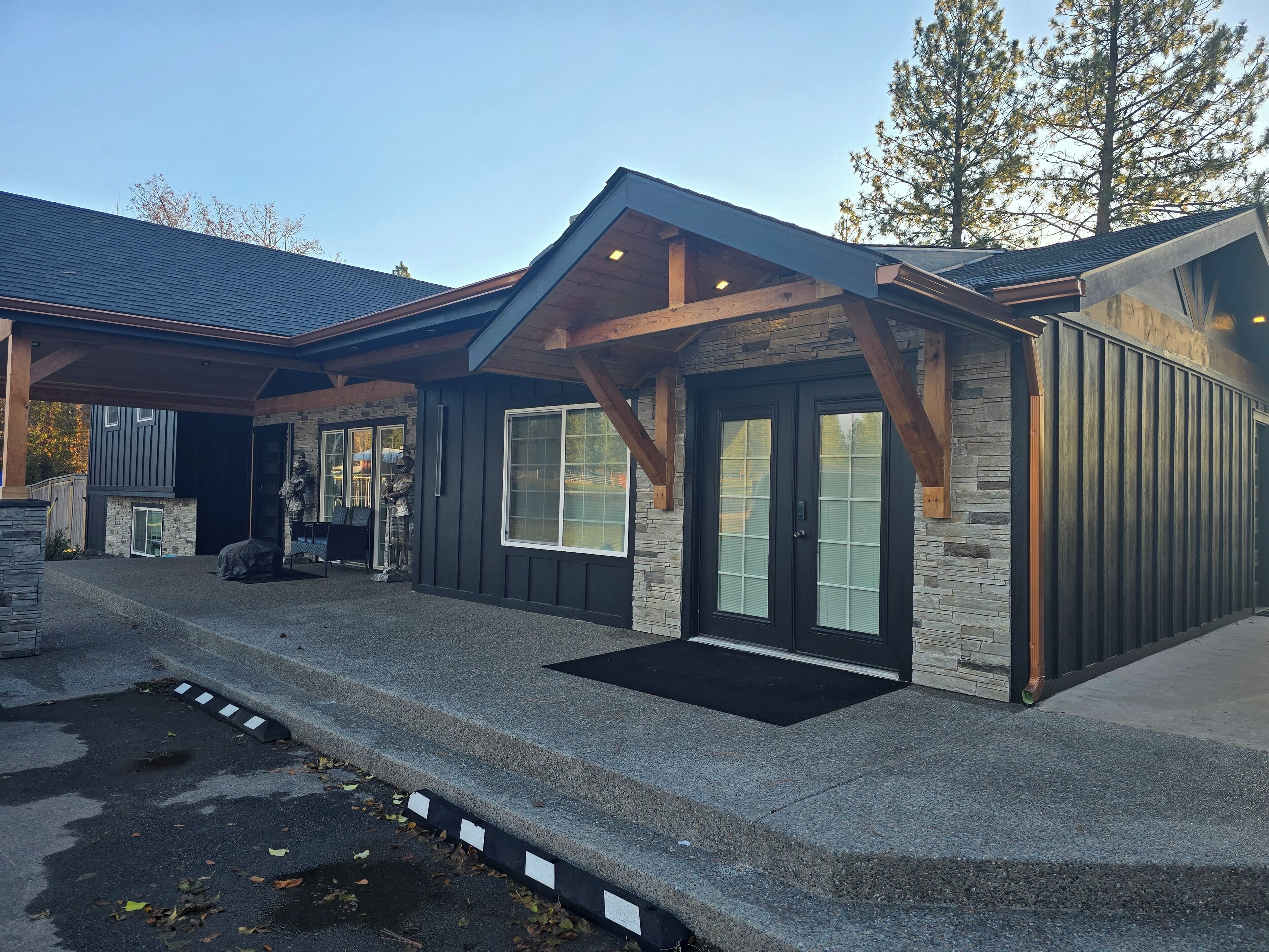 A modern house with a stone facade, large windows, and a covered porch.