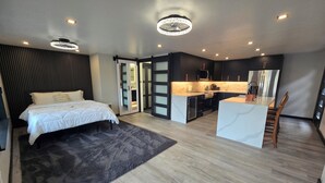 Ein modernes Schlafzimmer mit einem großen Bett, einer separaten Küchenzeile und einem Essbereich.