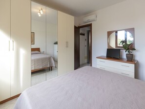 A bedroom with a bed, a wardrobe, a dresser, a television, and a potted plant. - Spacious three-room apartment near Lacona beach (Lacona)