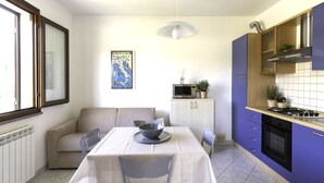 Una cocina compacta con una mesa de comedor, sillas, microondas y estufa.