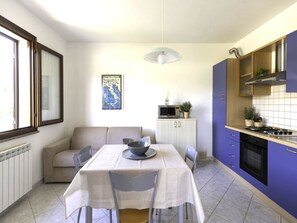 A compact kitchen with a dining table, chairs, a microwave, and a stove. - Spacious three-room apartment near Lacona beach (Lacona)