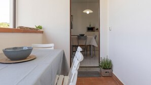 Un comedor con una mesa preparada para dos personas, una silla, un cuenco y una lámpara colgante.
