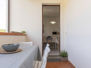 A dining area with a table set for two, a chair, a bowl, and a hanging light fixture. - Spacious three-room apartment near Lacona beach (Lacona)