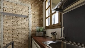 A kitchen with a brick wall, wooden countertop, stainless steel sink, and a window with blinds. - In the heart of Portoferraio's historic center! (Portoferraio)