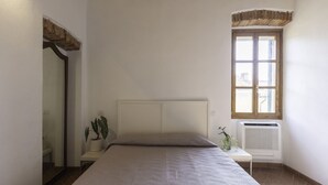 A bedroom with a large bed, a window with a view, a radiator, and a plant on the nightstand. - In the heart of Portoferraio's historic center! (Portoferraio)