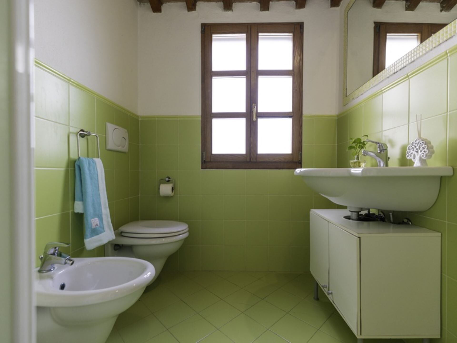 Ein Badezimmer mit Toilette, Bidet, Waschbecken und einem Fenster.