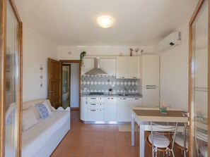 Eine kompakte Küche mit weißen Schränken, einem Gasherd und einer gefliesten Spritzschutzwand.